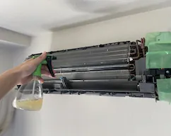 洗浄後の熱交換器に抗菌剤を吹き付けている実際の作業写真